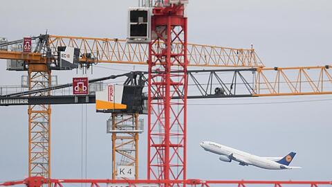 Eine Passagiermaschine der Lufthansa startet auf dem Frankfurter Flughafen hinter Baukränen.
