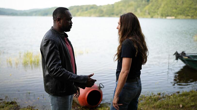 Der ortsans&auml;ssige Polizist Didier Bousquet (Otis Ngoi) erkl&auml;rt seiner neuen Kollegin No&eacute;mie Chastain (Laura Smet), was es mit dem Stausee auf sich hat.