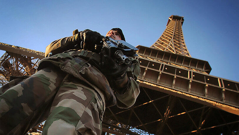 Ein Soldat steht vor dem Eiffelturm in Paris. Die Sicherheitsvorkehrungen sollen im ganzen Land immens verstärkt werden. Ein Soldat steht vor dem Eiffelturm in Paris. Die Sicherheitsvorkehrungen sollen im ganzen Land immens verstärkt werden.