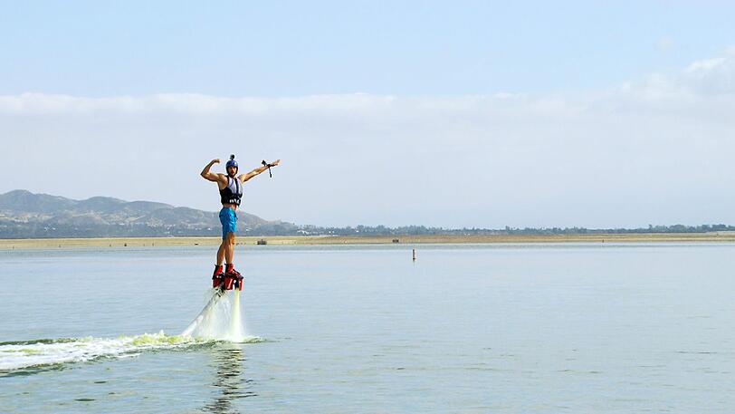 Oliver fliegt mit einem Flyboard übers Wasser.