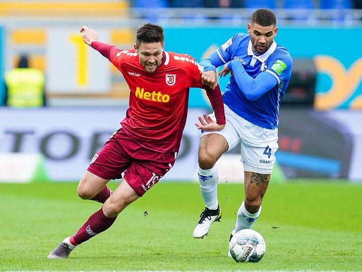 Regensburgs Andreas Albers (l.) und Darmstadts Victor Palsson kämpfen um den Ball. Foto: Uwe Anspach/dpa