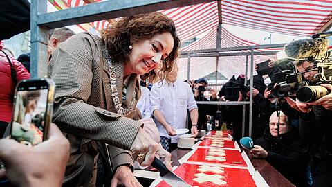 Amsterdams Bürgermeisterin Femke Halsema schneidet die lange Torte an.