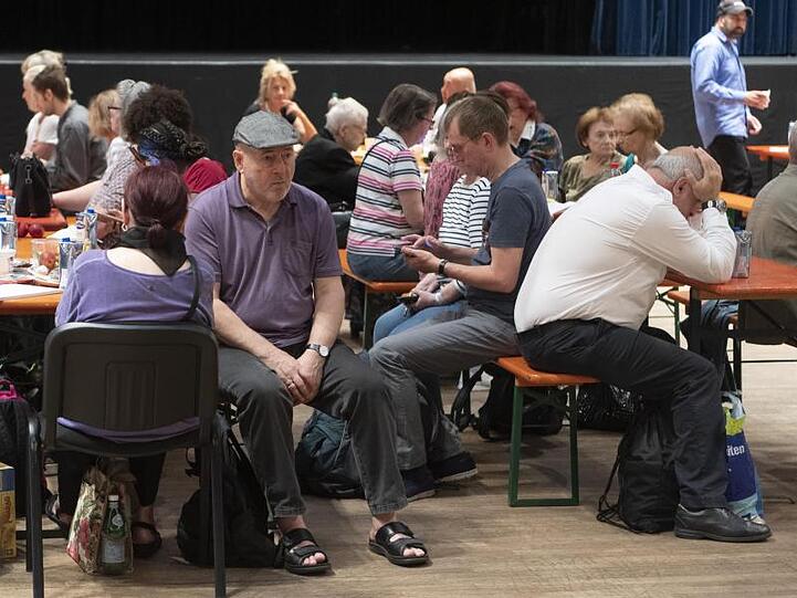 Menschen sitzen in der Sammelstelle des Roten Kreuzes außerhalb der Evakuierungszone.