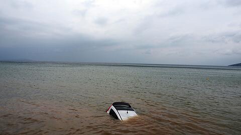 Ein Auto ist nach einem Rekordregen in Milina fast ganz im Meer versunken.