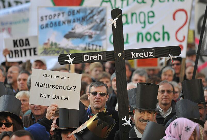 Teilnehmer einer Demonstration gegen den Bau der dritten Startbahn halten auf dem Marienplatz Plakate in die Höhe.