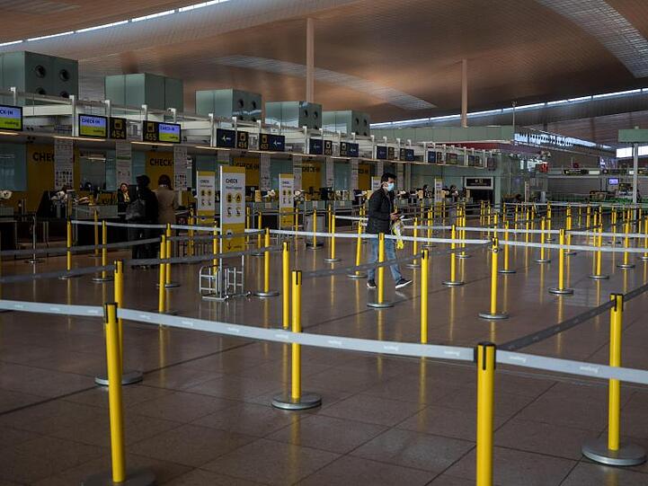 Ein Mann mit Mundschutzmaske im leeren Terminal eines Flughafens.