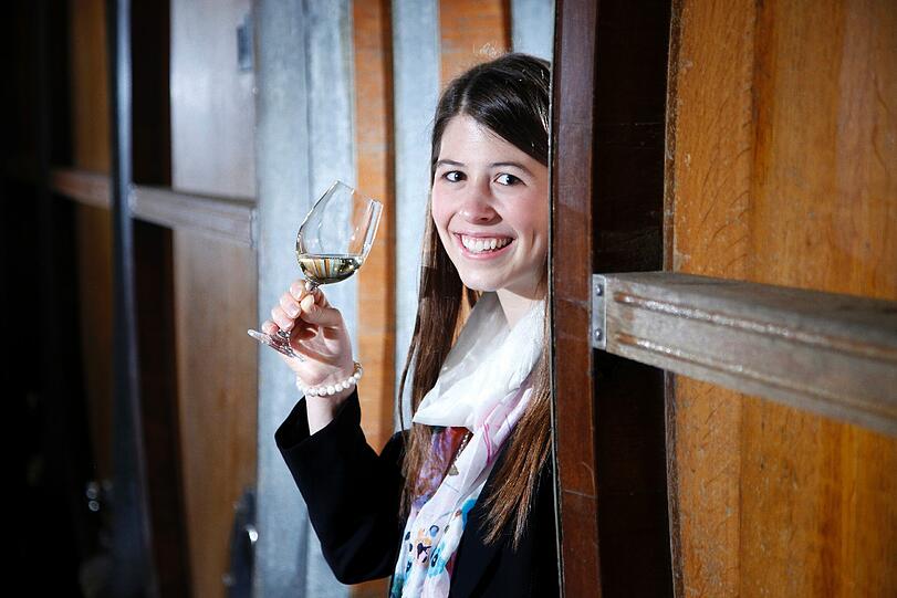 Die designierte fraenkische Weinkoenigin 2012/2013, Melanie Dietrich, posiert in Wuerzburg im Keller des Weinguts Buergerspital zum Heiligen Geist mit einem Glas Wein zwischen Faessern