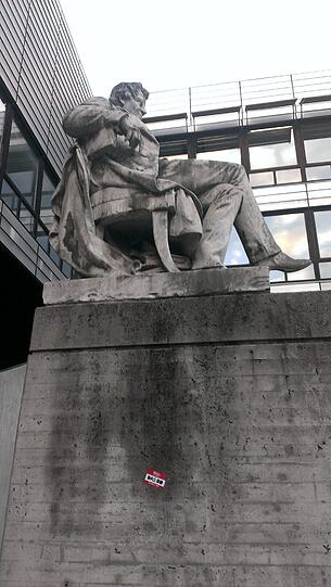 Die Aufkleber werben für ein Konzert im P1 - sogar auf der Statue des Physikers Georg Simon Ohm, nach dem die Maßeinheit für den elektrischen Widerstand benannt ist.
