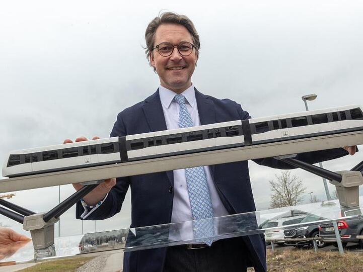 Andreas Scheuer (CSU) steht nach einer Pressekonferenz hinter einem Modell einer Magnetschwebebahn.