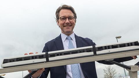 Andreas Scheuer (CSU) steht nach einer Pressekonferenz hinter einem Modell einer Magnetschwebebahn.
