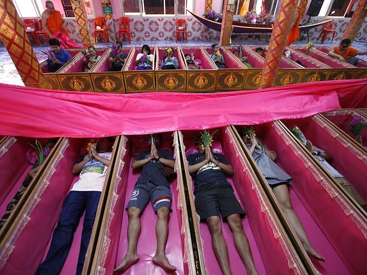 Gläubige liegen in rosa Särgen und beten während einer Zeremonie, die Tod und Wiedergeburt symbolisiert - und von Unglück befreit.