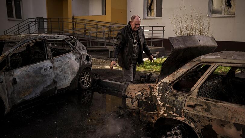 Ein Mann begutachtet sein verbranntes Auto nach einem russischen Angriff in Charkiw. Ein Mann begutachtet sein verbranntes Auto nach einem russischen Angriff in Charkiw.