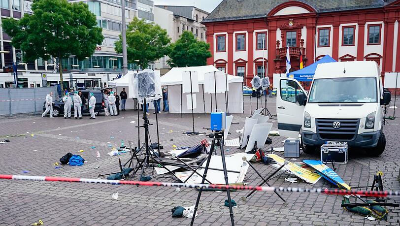 Mitarbeiter der Spurensicherung stehen auf dem Marktplatz hinter einem zertrümmerten Stand.