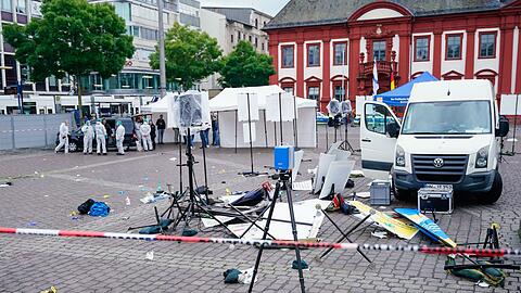 Mitarbeiter der Spurensicherung stehen auf dem Marktplatz hinter einem zertrümmerten Stand.