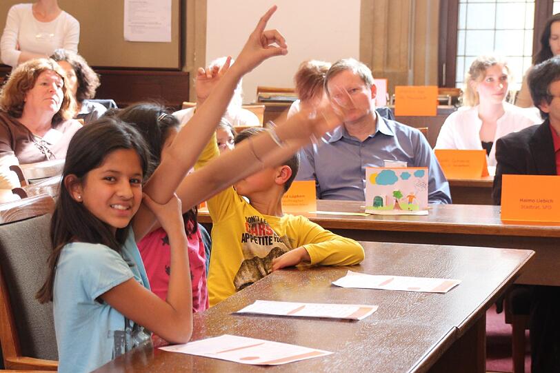 Der Sitzungssaal im Rathaus ist beinahe voll besetzt, mit kleinen Menschen in bunten Shirts mit Comicfiguren darauf.