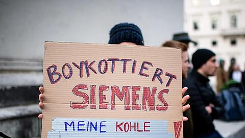 Eine Demonstrationsteilnehmerin hält während einer Protestaktion von Fridays for Future vor der Siemens Zentrale in München ein Schild in die Höhe.
