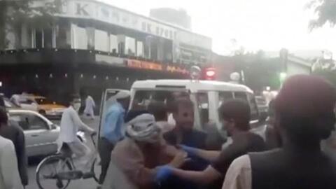 Menschen kümmern sich um eine verwundete Person in der Nähe der Explosion außerhalb des Flughafens in Kabul.