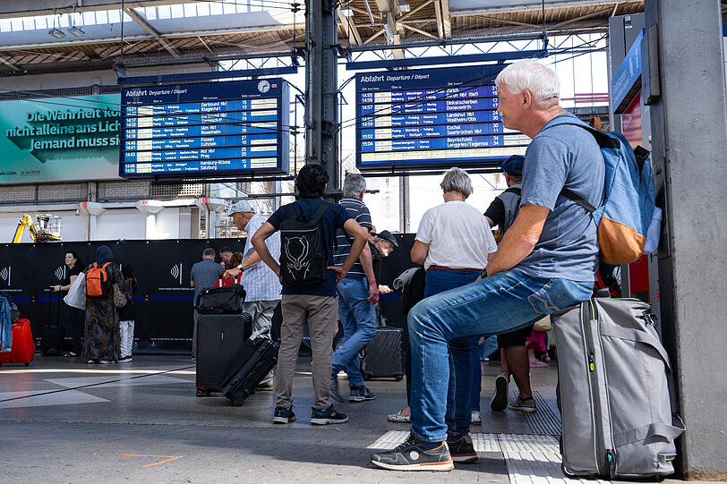 Reisende warten im Hauptbahnhof vor einer Anzeigetafel. Nach einem Oberleitungsschaden in München ist der Fernverkehr vom und zum Münchner Hauptbahnhof eingestellt.