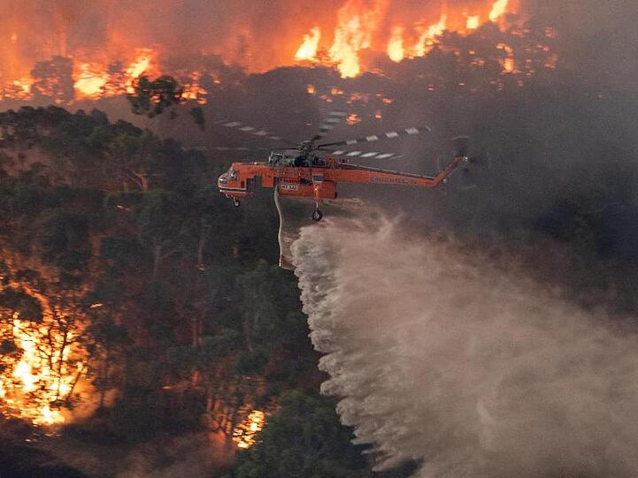 Ein Löschhubschrauber fliegt über ein Buschfeuer in der Nähe von Bairnsdale in der Region East Gippsland Shire im Bundesstaat Victoria.