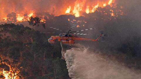 Ein Löschhubschrauber fliegt über ein Buschfeuer in der Nähe von Bairnsdale in der Region East Gippsland Shire im Bundesstaat Victoria.