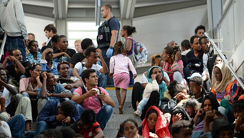 Flüchtlinge sitzen am Bahnhof in Rosenheim und warten darauf, registriert zu werden. Flüchtlinge sitzen am Bahnhof in Rosenheim und warten darauf, registriert zu werden.