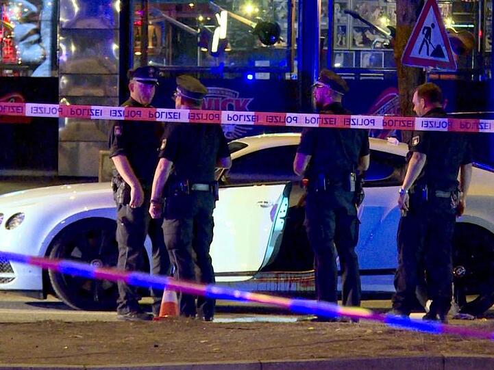 Polizisten stehen neben dem Auto des Rockerbosses auf dem Millerntorplatz an der Reeperbahn, nachdem die Schüsse gefallen waren.