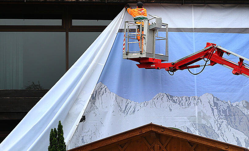 Das Alpenpanorama-Banner am Kurhaus in Garmisch wird abgehängt.