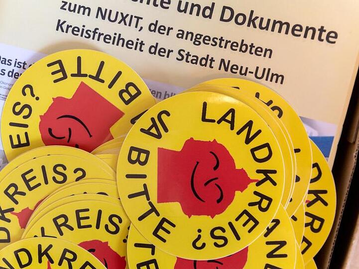 Aufkleber mit der Aufschrift "Landkreis? - Ja Bitte" liegen im Bayerischen Landtag. Foto: Peter Kneffel/Archivbild