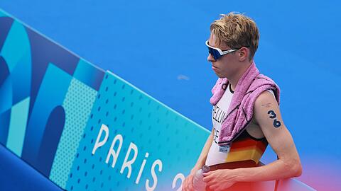 Triathlet Tim Hellwig lehnt nach dem Olympia-Rennen enttäuscht an einer Bande.