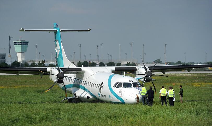 Mitarbeiter des Flughafens in München betrachten die Maschine der italienischen Fluggesellschaft, die am Donnerstag auf dem Münchner Flughafen notlanden musste. Das Flugzeug mit 62 Menschen an Bord hatte kurz nach dem Start in Richtung Venedig umdrehen müssen, weil sich Rauch in der Kabine entwickelt hatte. Bei der Landung wurden fünf Personen leicht verletzt, die Maschine kam neben der Landebahn zum Stehen.