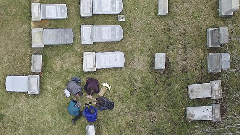 Betende versammeln sich in Philadelphia zwischen umgestoßenen Grabsteinen auf dem geschändeten jüdischen Mount Carmel Friedhof. Der Antisemitismus im Land wächst.