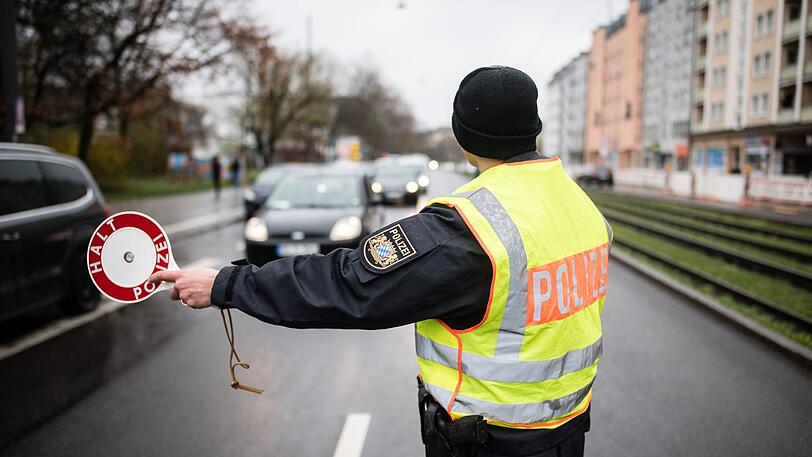 Ein Polizist stoppt an einer Kontrollstelle ein Fahrzeug mit seiner Kelle. Im Zuge der neu auferlegten Ausgangsbeschränkungen befragt die Polizei die Insassen von Fahrzeugen nach dem Grund und der Notwendigkeit ihrer Fahrt.