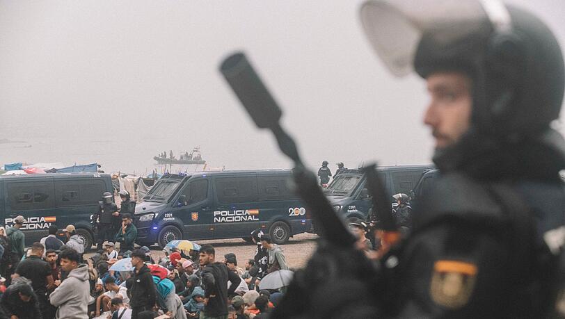 Migranten wurden in Ceuta von starken spanischen Polizeikr&auml;ften von einem H&uuml;ttenlager am Strand fortgebracht.