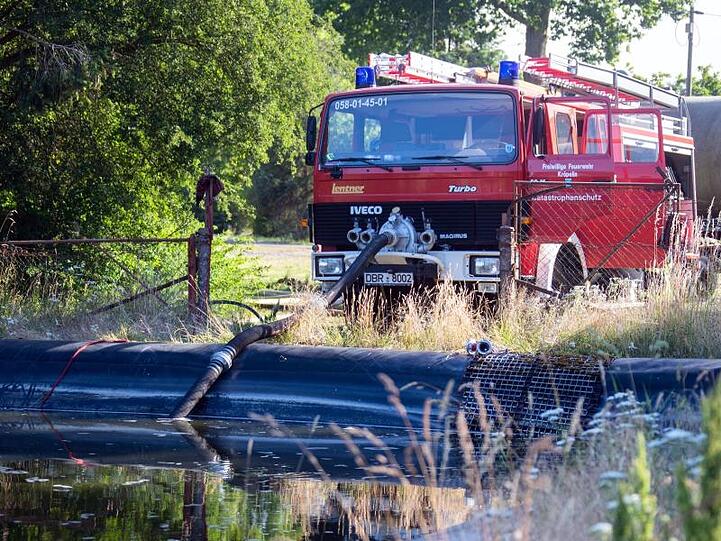 Feuerwehrleute pumpen Wasser aus einem Löschteich.