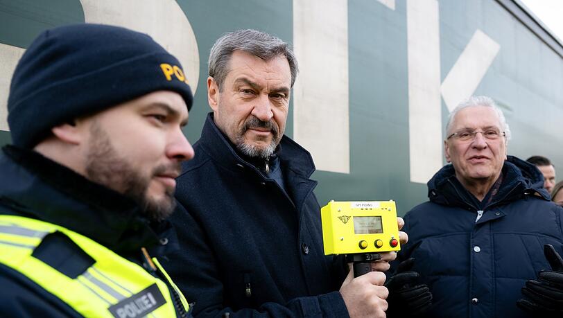 Markus Söder (M, CSU), Ministerpräsident von Bayern, und Joachim Herrmann (r, CSU), Innenminister von Bayern, nehmen am Grenzübergang Oberaudorf an einer Kontrolle eines Lkw teil. Söder hält dabei einen Herzschlagdetektor in den Händen. +++ dpa-Bildfunk +++