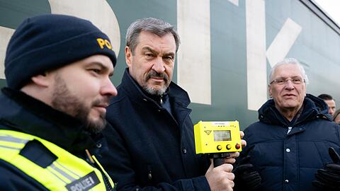Markus Söder (M, CSU), Ministerpräsident von Bayern, und Joachim Herrmann (r, CSU), Innenminister von Bayern, nehmen am Grenzübergang Oberaudorf an einer Kontrolle eines Lkw teil. Söder hält dabei einen Herzschlagdetektor in den Händen. +++ dpa-Bildfunk +++