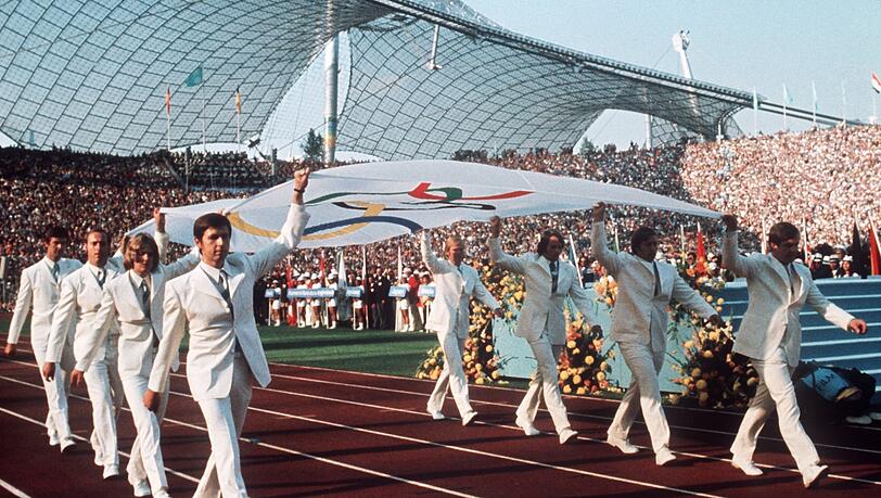 Deutsche Sportler tragen 1972 bei der Eröffnungsfeier die Olympia-Fahne in das Münchner Olympiastadion (Archivbild). Deutsche Sportler tragen 1972 bei der Eröffnungsfeier die Olympia-Fahne in das Münchner Olympiastadion (Archivbild).