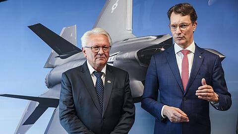 Papperger und Wüst vor einem Bild des F-35-Flugzeugs. Ende nächsten Jahres soll das erste Rumpfmittelteil dieses Tarnkappenbombers in Weeze fertig sein.