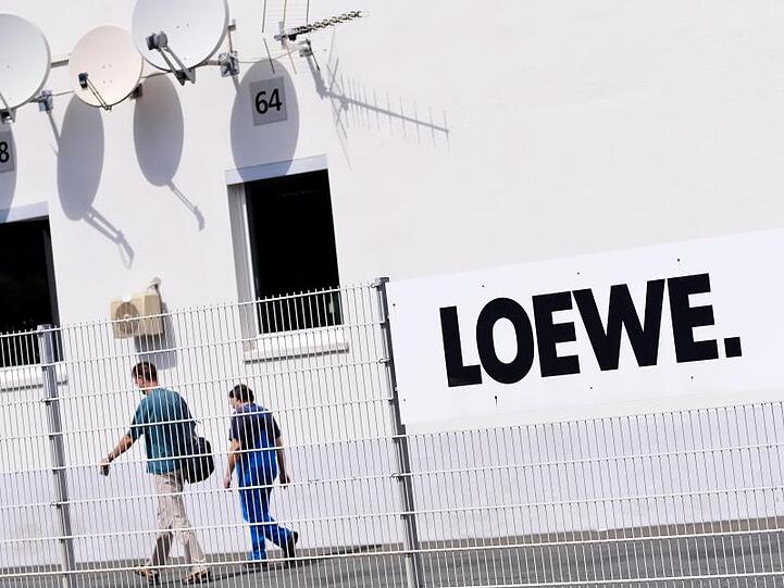 Zwei Mitarbeiter gehen über das Gelände des Elektronikherstellers Loewe in Kronach. Foto: David Ebener/Archivbild