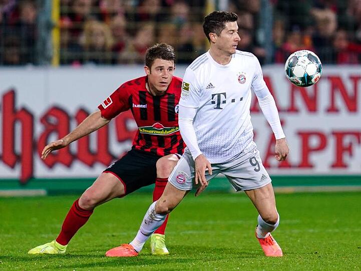 Freiburgs Dominique Heintz (l.) und Münchens Robert Lewandowski kämpfen um den Ball. Foto: Uwe Anspach/dpa