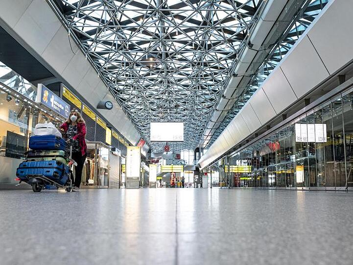 Eine Frau mit Mundschutzmaske läuft durch die ansonsten leere Haupthalle des Flughafens Tegel.