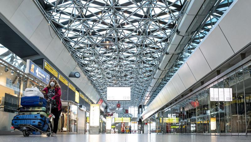 Eine Frau mit Mundschutzmaske läuft durch die ansonsten leere Haupthalle des Flughafens Tegel. Eine Frau mit Mundschutzmaske läuft durch die ansonsten leere Haupthalle des Flughafens Tegel.