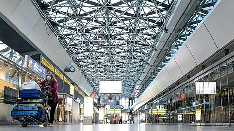Eine Frau mit Mundschutzmaske läuft durch die ansonsten leere Haupthalle des Flughafens Tegel.