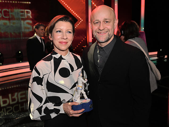 Mareike Engelhardt steht neben Jürgen Vogel und zeigt ihren Preis als Newcomer Regie für ihren Film "Rabia" nach der Show im Prinzregententheater.