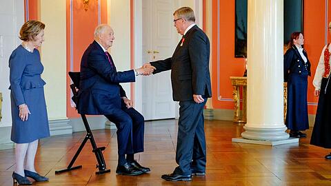 König Harald empfängt Besucher im Sitzen.
