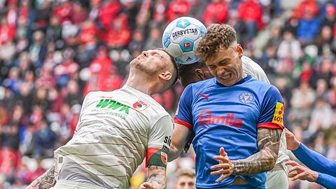 Rasant ging es zu auf dem Platz. Kiels Nicolai Remberg (r) und Augsburgs Kapitän Jeffrey Gouweleeuw beim Kopfballduell.