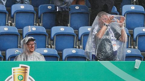 Zuschauer schützen sich vor dem Regen.