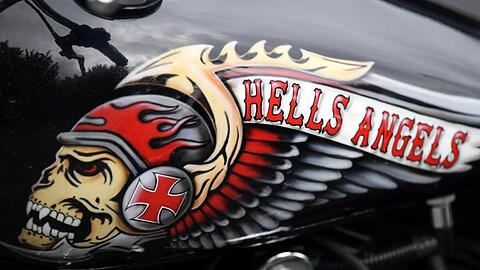 Das Hells Angels-Emblem, ein Totenkopf mit Helm und Flügeln, auf einem Tank eines abgestellten Motorrads.