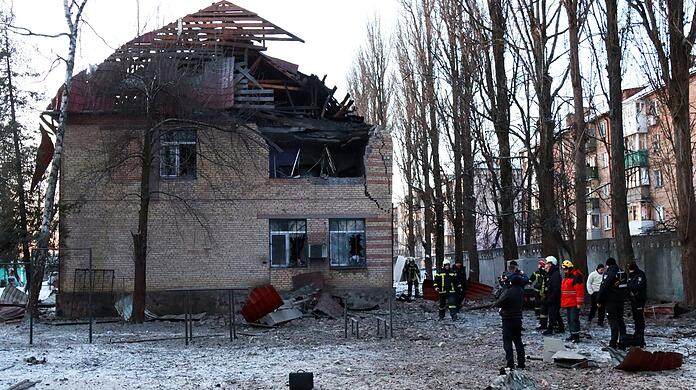Rettungskräfte stehen neben einem beschädigten Gebäude in Kiew.