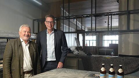 Josef Schr&auml;dler (l.) und Minister Markus Blume zeigen das Herzst&uuml;ck des Lokals: die Theke mit Gneis aus dem Valsertal.